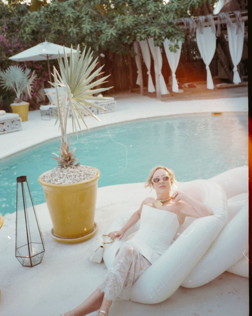 editorial film wedding photograph of a bride sitting on floaties by the pool at Ser Casasandra Holbox Mexico