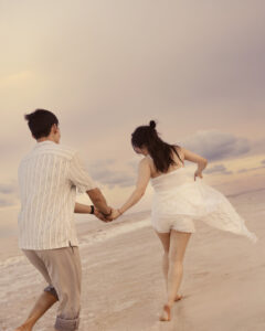 couple running on the beach with a soft pink sunset