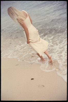 Bride walking barefoot along Half Moon Bay after ceremony shot on 35mm film